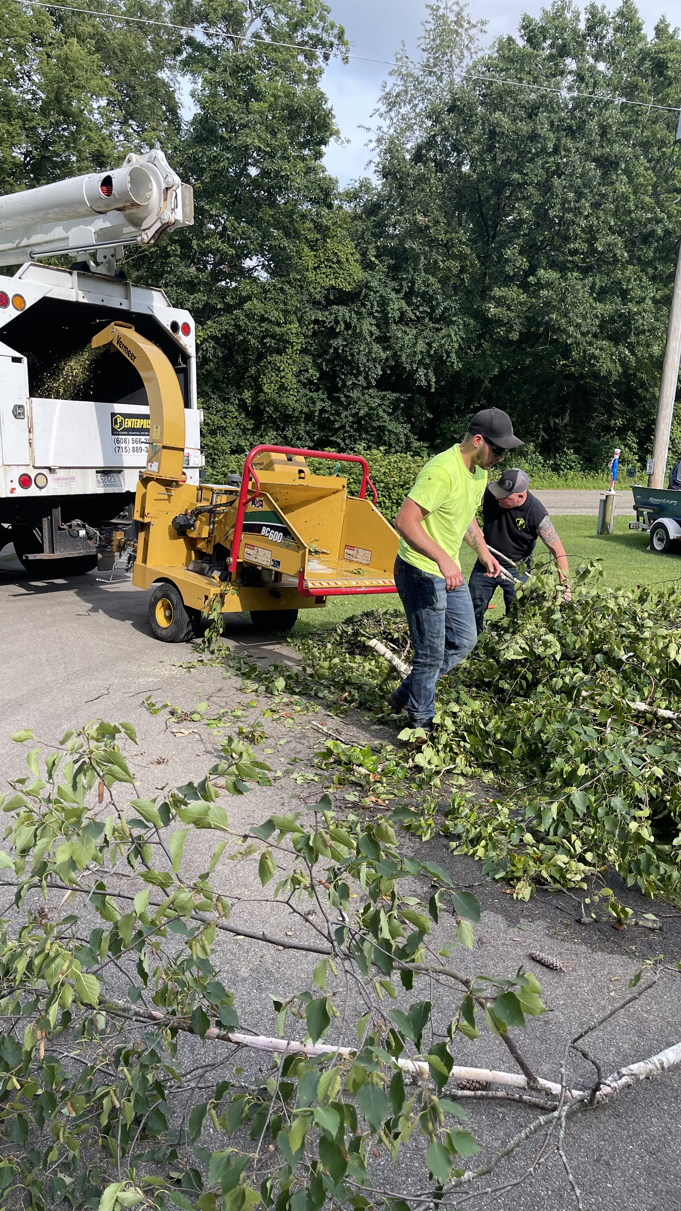 Crew cleaning up tree debris next to a chipper truck