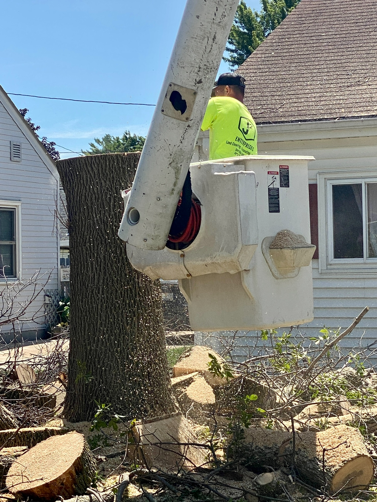 Crew member in a bucket working near a tree stump